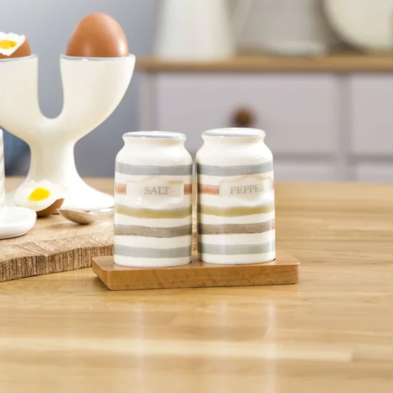 Керамічні сільничка та перечниця на дерев'яній таці